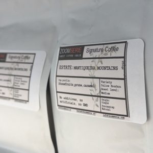 Close-up of a coffee bag label that says “Signature Coffee, Estate Mantiqueira Mountains,” with flavor notes like stone fruits, prune, caramel and roast level listed as Medium.
